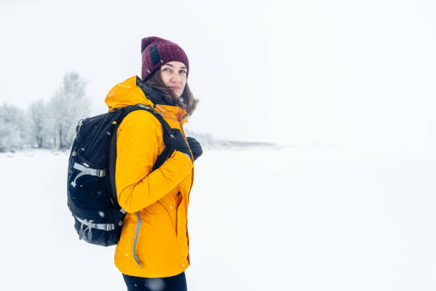 istock Woman with backpack on a winter walk outdoors. Defocused winter forest on background. 1296294272