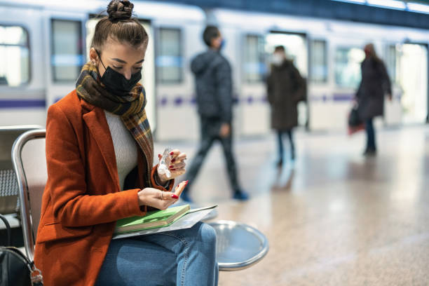 istock Student disinfecting her hands while waiting for the train at the station 1296294322