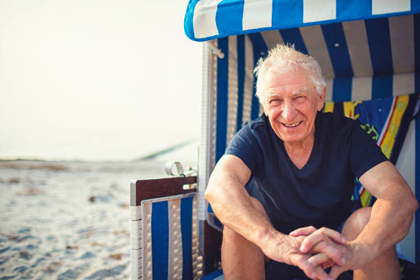 Friendly old gentleman enjoys vacation on the Baltic Sea and sitting in a beach chair on Hiddensee/ Germany Friendly old gentleman enjoys vacation on the Baltic Sea and sitting in a beach chair on Hiddensee/ Germany baltic sea people stock pictures, royalty-free photos & images