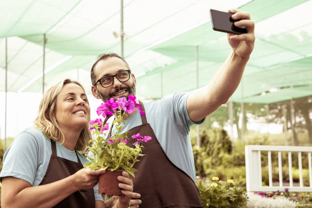 istock Bearded man and blonde woman doing selfie with petunia 1296295996