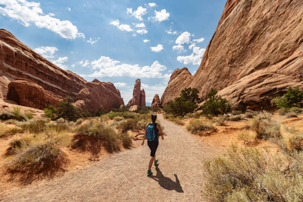Adventures in desert of USA Southwest: Woman hiking in a desert landscape at Capitol Reef Under Corona arch: Woman hiking near Canyonlands, Moab canyonlands national park stock pictures, royalty-free photos & images