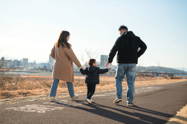 手をつないで歩く両親と息子の背面図 - 住宅地 写真 ストックフォトと画像