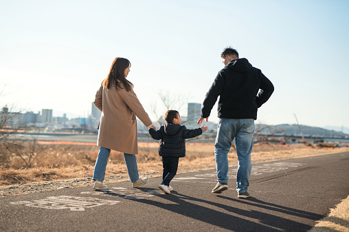 Rear view of parents and son walking with holding hands