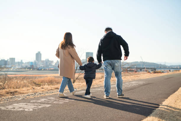 istock Rear view of parents and son walking with holding hands 1296298070
