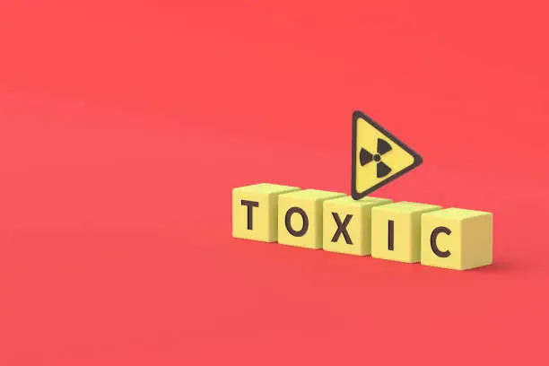 Photo of Cubes with word toxic near sign of radiation hazard on red background. Copy space. 3d rendering