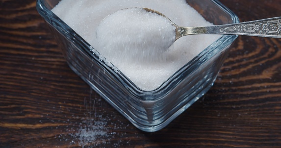 Taking a teaspoon of sugar from the glass sugar bowl