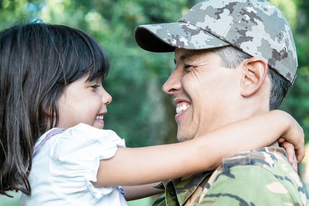 istock Cheerful dad in camouflage uniform holding little daughter 1296302341