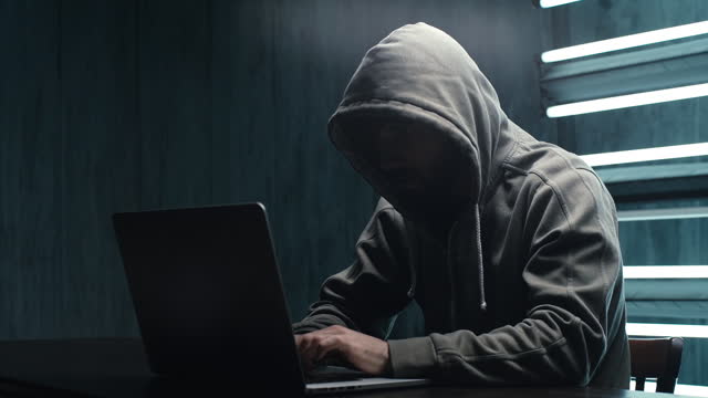 Unrecognizable hacker man stretching hands and starting to typing on laptop and breaking password.