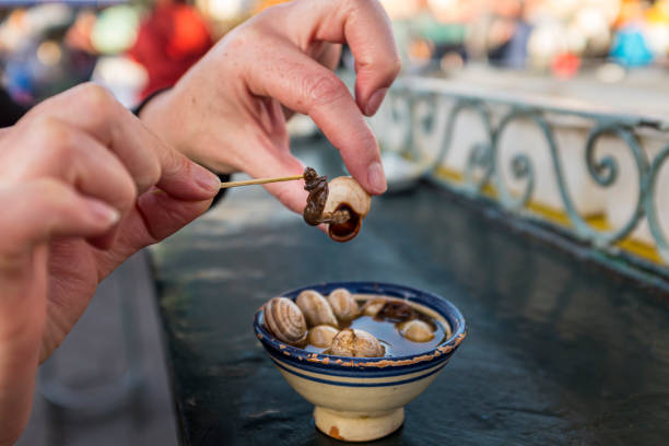 mulher extraindo caracol de sua concha de uma sopa no marrocos - jema el fna - fotografias e filmes do acervo