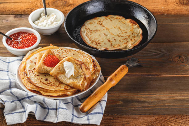 istock Stack of russian pancakes blini with red caviar, fresh sour cream 1296304674
