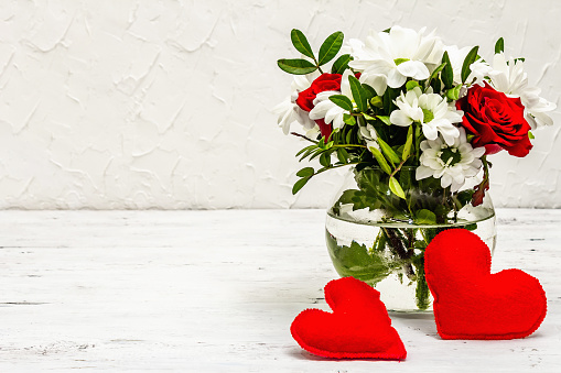 A bouquet of fresh flowers and red felt hearts. Valentine's day or Wedding concept. White old planks background, copy space