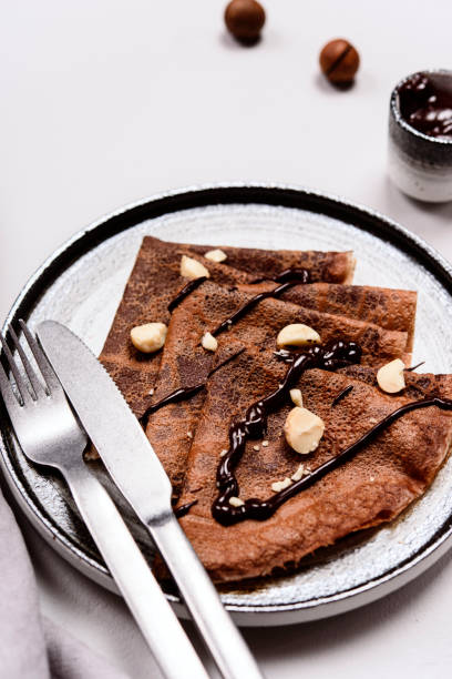 istock Chocolate Crepes with Chocolate Sauce served with macadamia nuts on a plate 1296307794