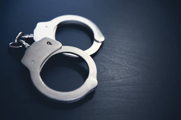 Crime and violence concept with handcuffs Handcuffs on wooden background. Crime and violence concept. criminal stock pictures, royalty-free photos & images