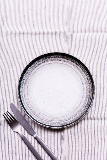 istock Empty pottery plate and cutlery on white linen tablecloth 1296311485