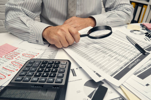 istock Business analysis and accounting concept - businessman working with document, spreadsheet, using calculator, tablet pc. Office desk closeup. 1296311650