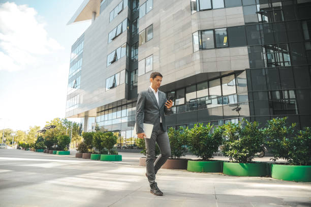 istock Businessman using phone, walking in front of the office building 1296311651