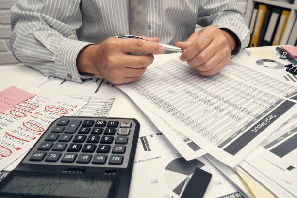 istock Business analysis and accounting concept - businessman working with document, spreadsheet, using calculator, tablet pc. Office desk closeup. 1296311712