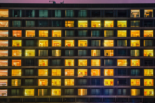 Building facade with windows and rooms pattern. The exterior features living spaces with people living in a shared communal space Building facade shows a windows and rooms pattern at night. The exterior features illuminated and dark living spaces with people living like neighbours in a shared communal space. Copenhagen, Denmark college dorm photos stock pictures, royalty-free photos & images