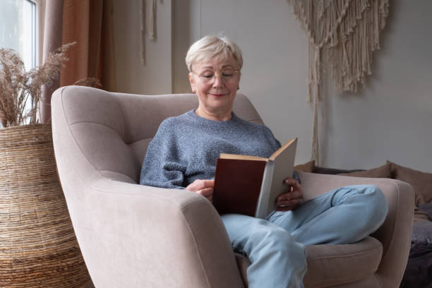istock Senior caucasian woman at home reading book 1296311854