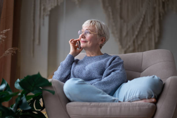 istock Senior woman talking on mobile phone at home 1296312246