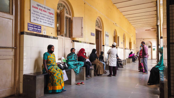 A General Hospital Corridor where people are seen sitting and waiting for their turn for a Preliminary Covid 19 Medical Test at Mysuru in Karnataka,India. An Old General Hospital Corridor view where patients are seen sitting and waiting for their turn for a Preliminary Covid 19 Medical Test at Mysuru in Karnataka,India. india hospital stock pictures, royalty-free photos & images