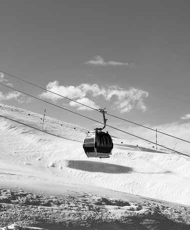 Snowy slope and gondola lift on ski resort at windy sun day. Caucasus Mountains at winter, Shahdagh, Azerbaijan. Black and white toned image. High contrast.