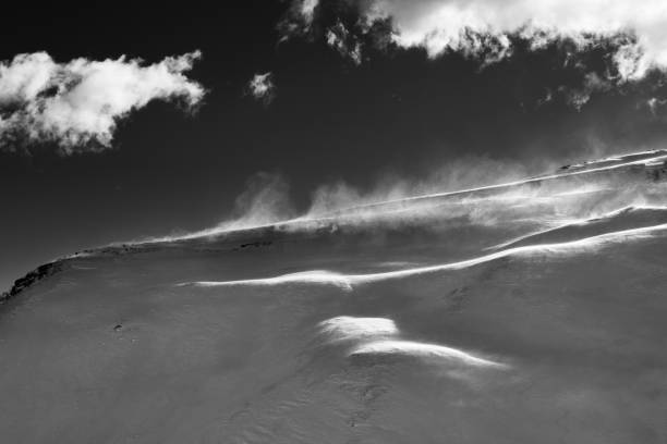 Off-piste slope during blizzard and sunlit sky with clouds