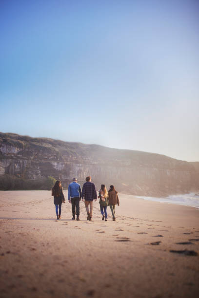 istock Friends group walking on the beach at sunset 1296316706