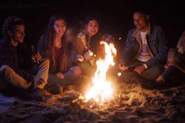 gruppo di amici che mangiano marshmallow e bevono falò - friendship camping night campfire foto e immagini stock