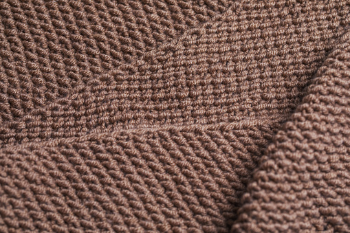 Texture of knitted fabric from brown yarn. Traditional hobby.