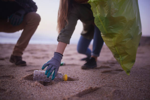 istock People picking up trash on the beach during sunset 1296317646