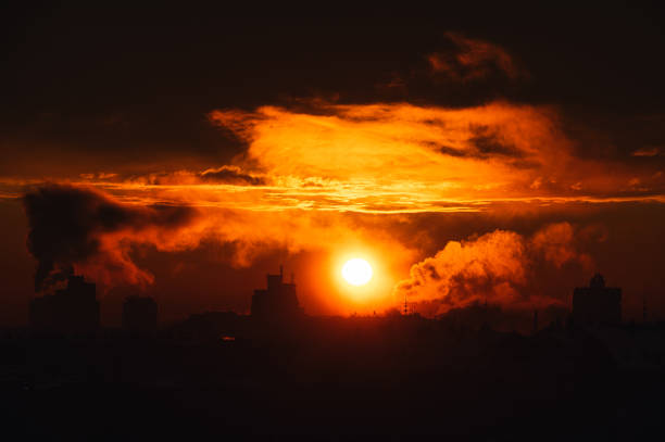 Smoke bellowing from chimney during sunrise on a harsh winter day city filled with snow