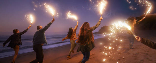 Group of friends running with sparklers on the beach Back-view of group of young friends running with sparklers on the beach at night polish beach stock pictures, royalty-free photos & images