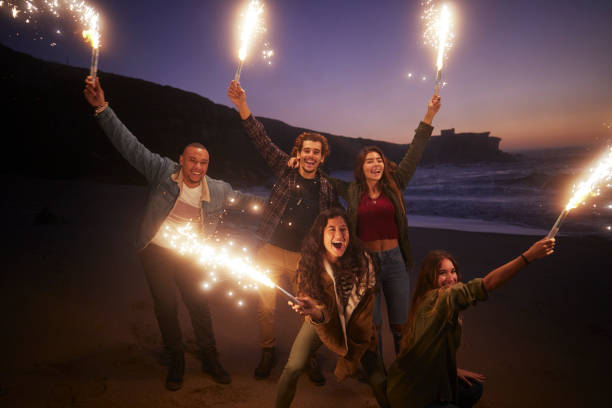 istock Friends holding sparklers looking at the camera on the beach 1296317968