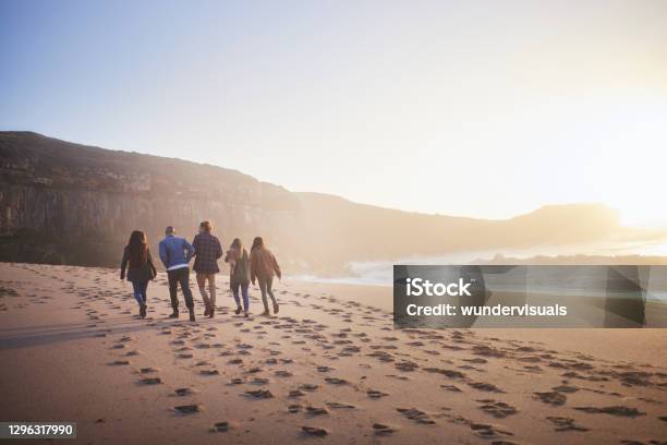 Group Of Friends Walking Together On The Beach At Sunset Stock Photo - Download Image Now