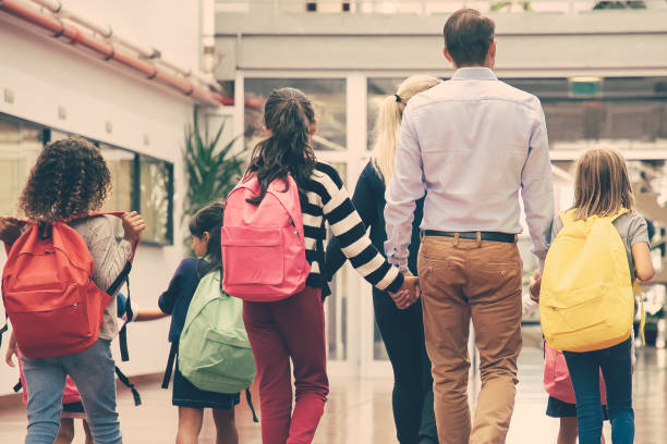 istock Schoolchildren with bright backpacks walking through hallway 1296318045