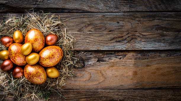 istock Straw nest with gold and bronze colored Easter eggs on rustic wooden table. Copy space 1296318253