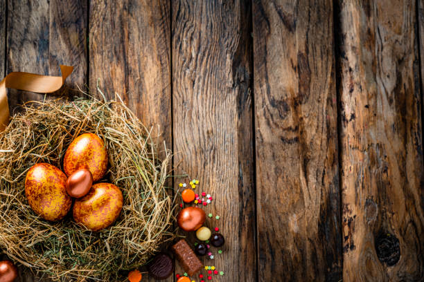 istock Gold and bronze colored Easter eggs and chocolate candies on rustic wooden table. Copy space 1296318923