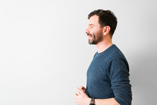 Side view of an good-looking man in love looking and smiling at his partner or girlfriend in front of a white background