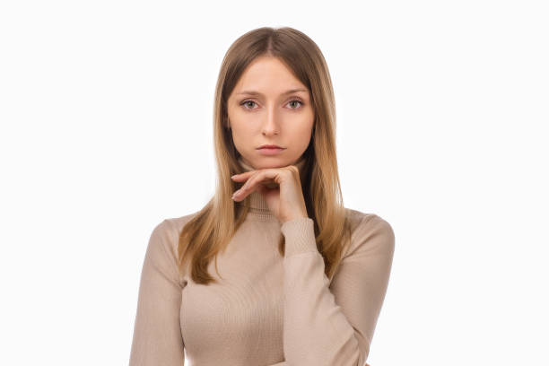 istock Pensive blond girl with thoughtful expression, keeps hand on chin, plans something or makes choice 1296319289