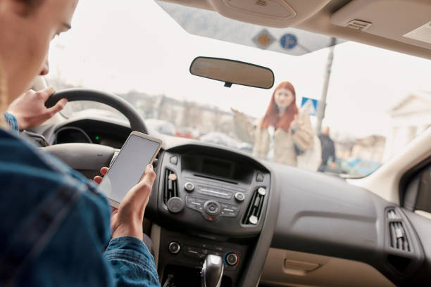 rozproszony młody mężczyzna kierowca patrząc na ekranie swojego telefonu komórkowego podczas jazdy nad pieszym. koncepcja technologii i transportu - driving text messaging accident car zdjęcia i obrazy z banku zdjęć