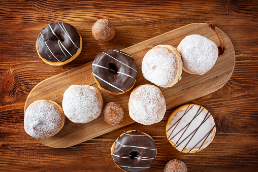 Different varietys sweet donuts on rustic wood. Food photography with space for text. Top view.