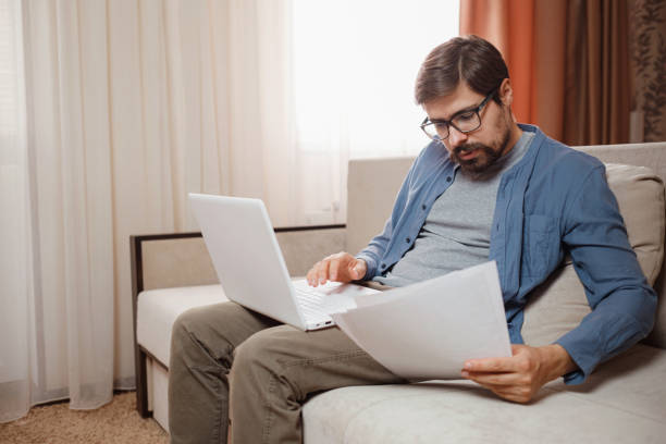 istock Entrepreneur works with a laptop and keeps a document in a home office 1296324373