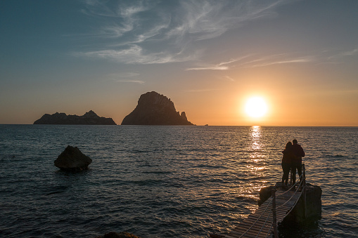 Es Vedra island at sunset with a couple in love. Ibiza Island. Balearic Islands Spain