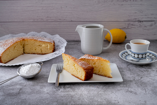 Spongy lemon sponge cake accompanied by a cup of coffee and milk