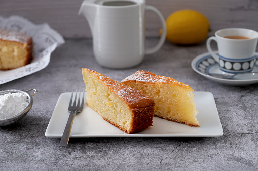 Spongy lemon sponge cake accompanied by a cup of coffee and milk