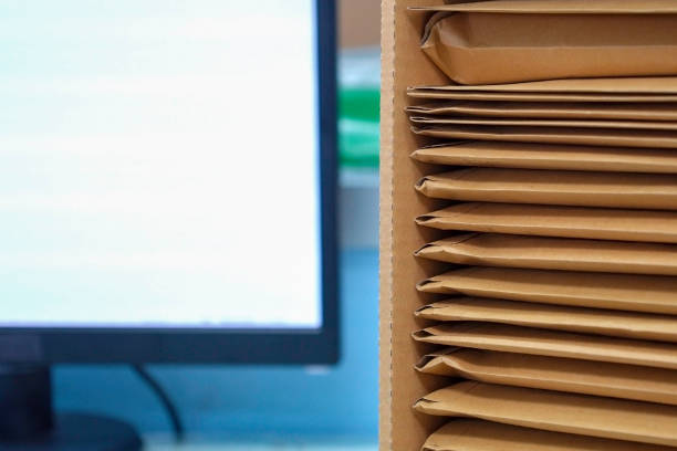 istock Stack of documents in brown envelops waiting to be converted to data saved to the computer. 1296325355