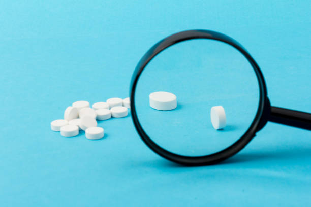istock Concept - pharmaceutical testing, testing of medicines, magnifying glass, tablets on a blue background. Doping control. 1296326018