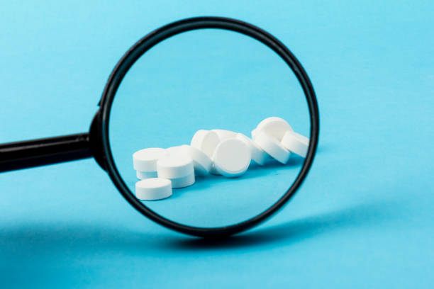 istock Concept - pharmaceutical testing, testing of medicines, magnifying glass, tablets on a blue background. Doping control. 1296326058