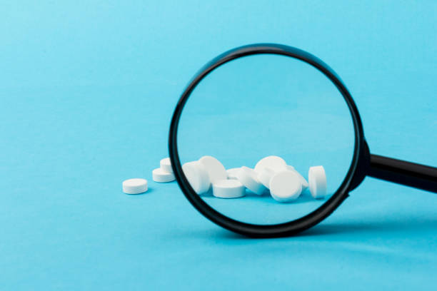 istock Concept - pharmaceutical testing, testing of medicines, magnifying glass, tablets on a blue background. Doping control. 1296326388